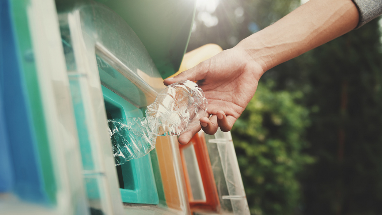 people putting plastic bottle in to recycle bin at park